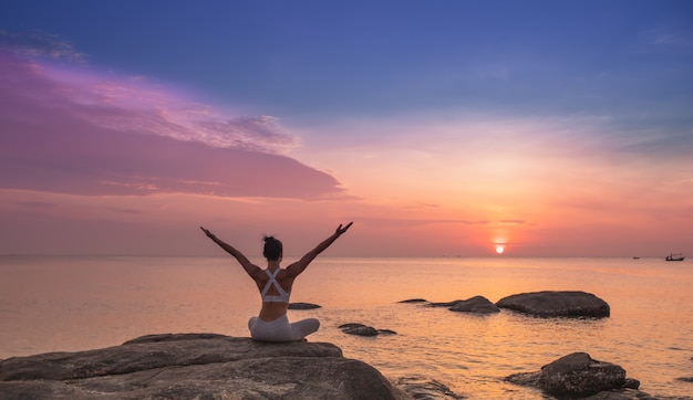 Foto chica practicando yoga en una roca