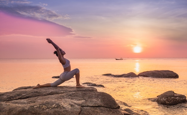 Chica practicando yoga en una roca