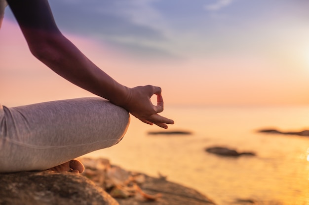 Foto chica practicando yoga en una roca