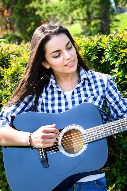 Chica en un prado verde tocando la guitarra