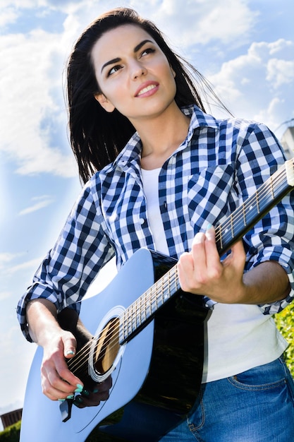 Chica en un prado verde tocando la guitarra