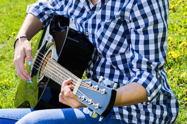 Chica en un prado verde tocando la guitarra