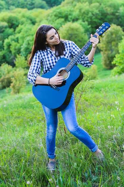 Chica en un prado verde tocando la guitarra