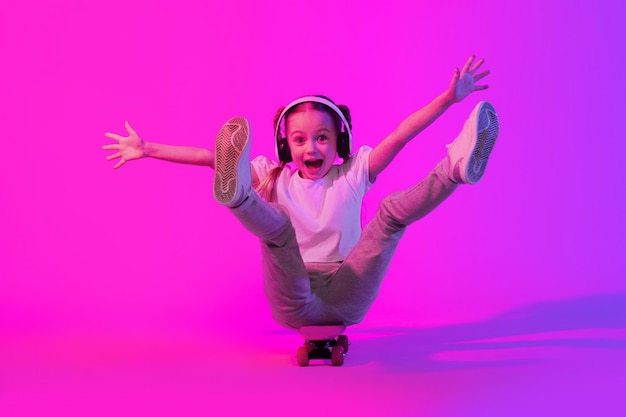 Chica preadolescente linda emocional posando con monopatín en el fondo del estudio