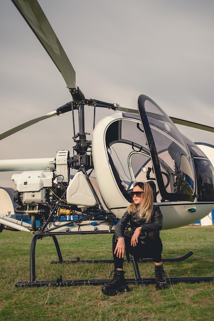 Chica preadolescente rubia confiada sentada en el escalón de un helicóptero abierto