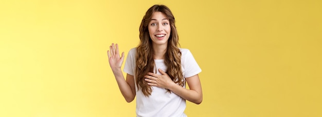 Foto la chica se presenta amistosa alegre conversación casual sonriendo ampliamente sostiene la mano el corazón levanta