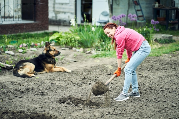 Chica de primavera cava un jardín con una pala en el jardín