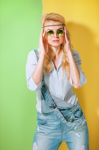 Chica de primavera en gafas de sol de moda sobre una superficie de color brillante