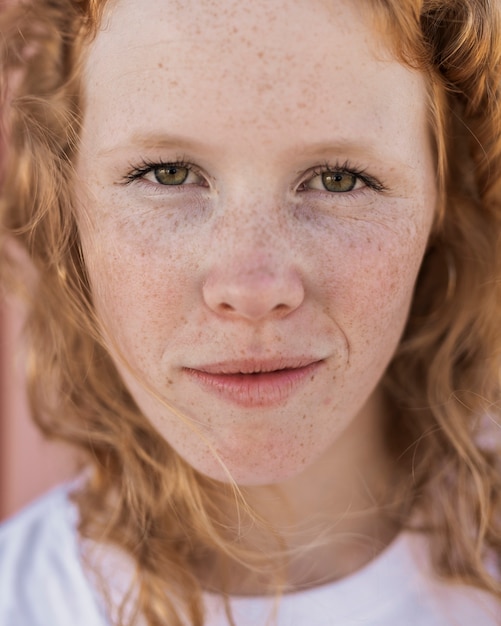 Foto chica de primer plano con pecas mirando a cámara