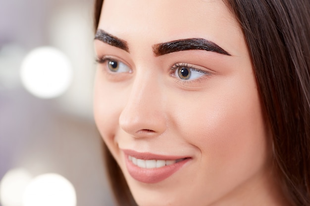 Foto chica durante el procedimiento de maquillaje permanente de las cejas.