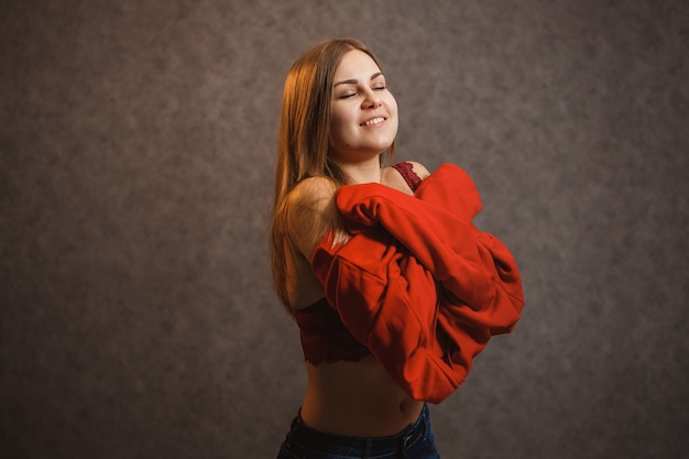 Chica se prueba un suéter rojo sobre un fondo gris