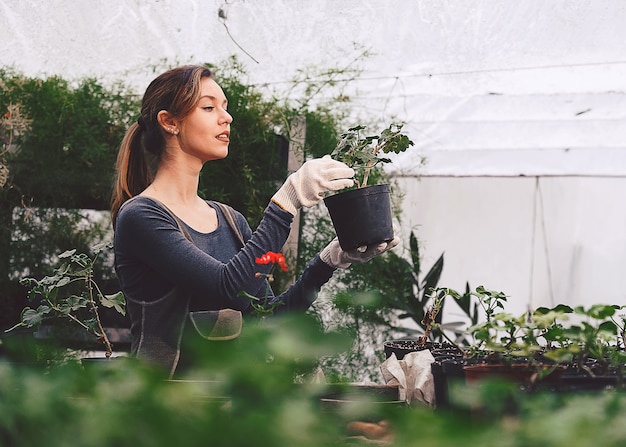 Chica que trabaja en el jardín con plántulas en macetas