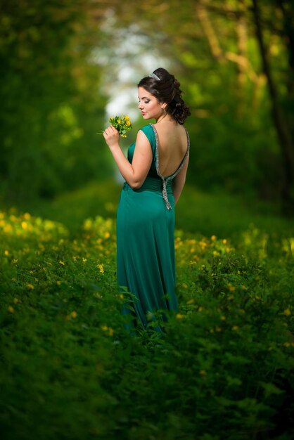 Foto chica con un ramo en un campo entre los verdes.