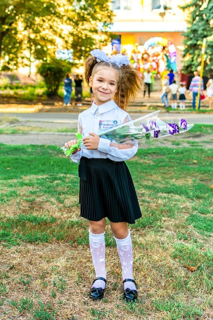 Chica con un ramo de flores con lazos durante la celebración del primero de septiembre