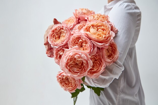 Chica con un ramo de hermosas rosas rosadas sobre un fondo gris. Día de la Madre, Día de San Valentín