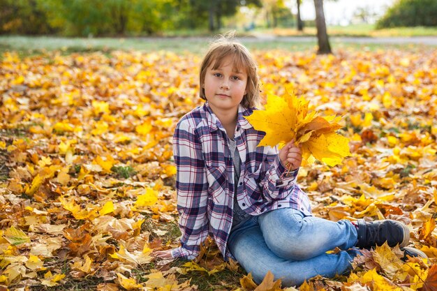 Chica con un ramo de hojas amarillas de otoño.