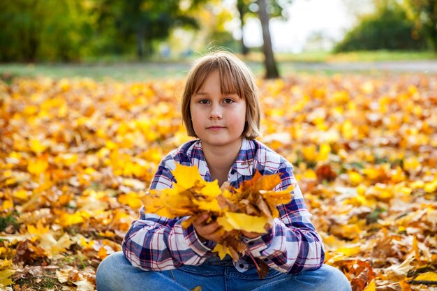 Chica con un ramo de hojas amarillas de otoño.