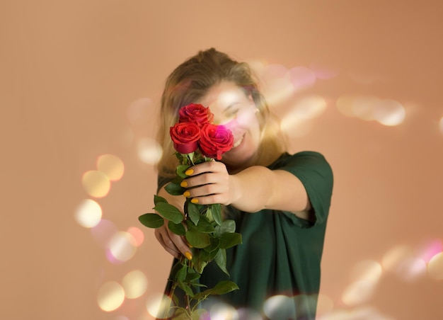 Chica con ramo de rosas rojas Ramo primaveral de rosas rojas en manos de mujer sobre fondo beige claro