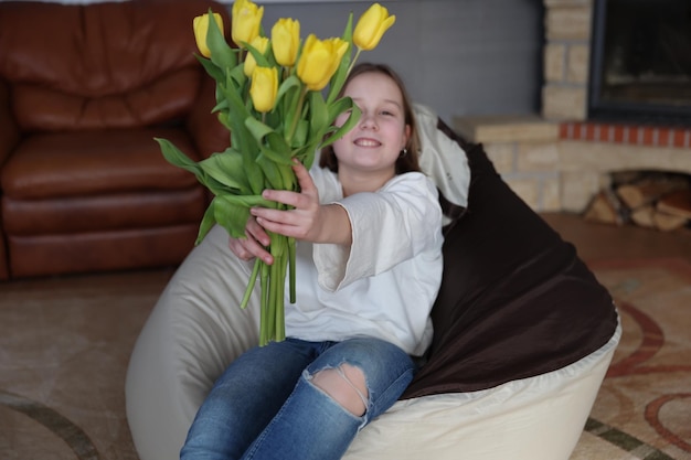 Chica con un ramo de tulipanes amarillos en la habitación.