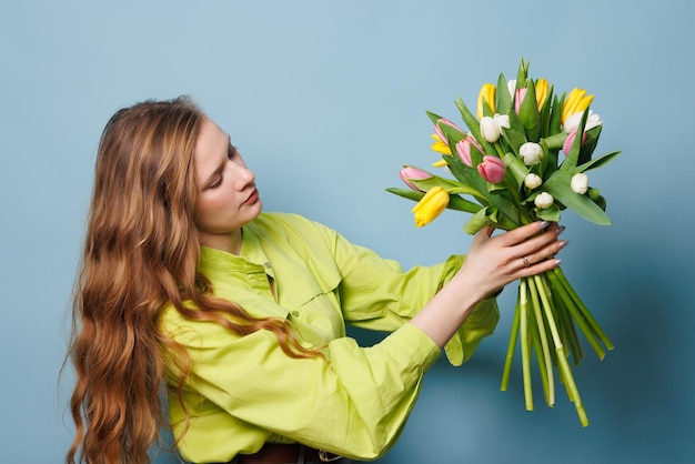 chica con un ramo de tulipanes de primavera en un fondo azul limpio flores de primavera