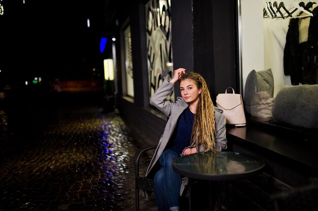 Chica con rastas caminando por la calle nocturna de la ciudad