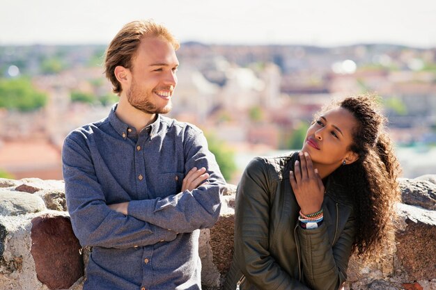 Chica de raza mixta joven pensativa con un amigo caucásico de pie y relajándose juntos como concepto de amistad y unión de diversidad