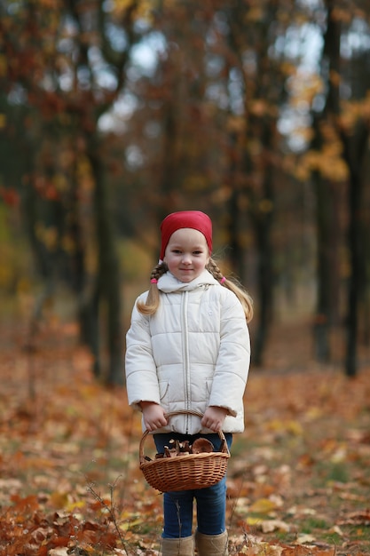 Chica recogiendo setas en el bosque de otoño