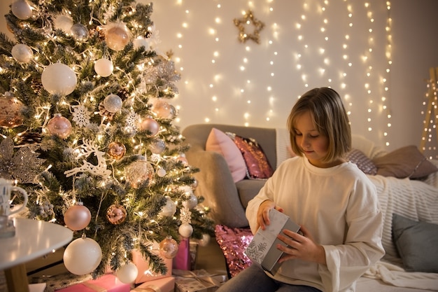 Chica con un regalo en el árbol de Navidad