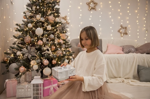 Chica con un regalo en el árbol de Navidad