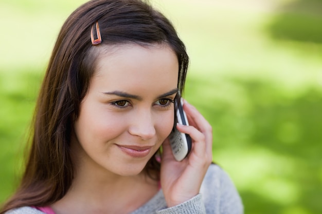 Chica relajada joven hablando por teléfono en un parque