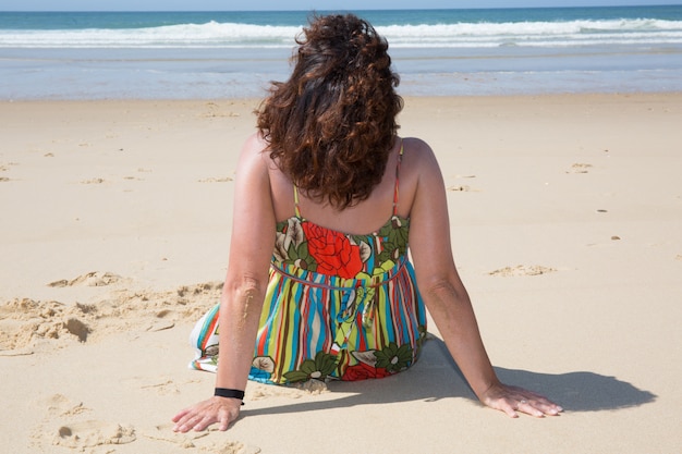 Chica relajante en la playa con un vestido de color