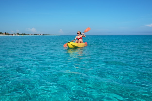 Chica rema un kayak en las aguas turquesas