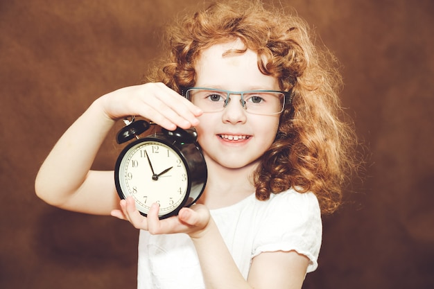 Foto chica rizada con reloj despertador.