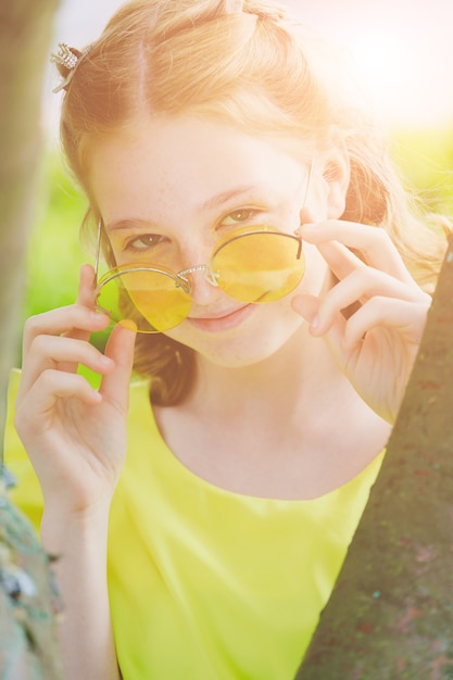 Chica roja con gafas amarillas en la naturaleza en verano. Foto de alta calidad