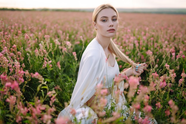 Chica romántica de belleza al aire libre al atardecer mujer joven en ropa elegante posando en el campo floreciente