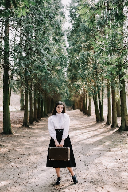 Chica romántica con una maleta vintage en el concepto de viaje de vacaciones de aventura en el parque