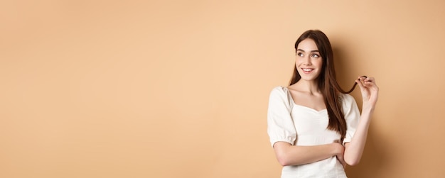 Foto chica romántica pensativa pensando mirando a la izquierda en el espacio vacío y jugando con la hebra de cabello persona sonriente