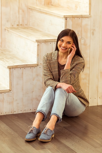 Chica en ropa casual, hablando por teléfono y sonriendo.