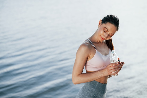 Foto chica en ropa deportiva está contra el lago en la pared