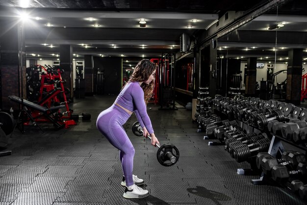 Una chica en ropa deportiva en un gimnasio profesional trabaja con equipos de fitness.