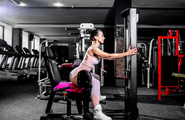 Una chica en ropa deportiva en un gimnasio profesional trabaja con equipos de fitness.