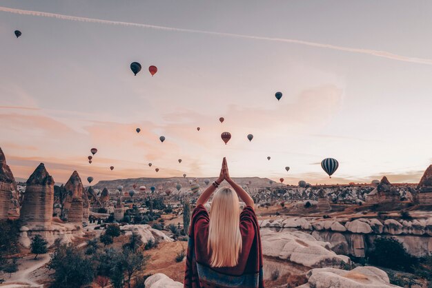 Chica en ropa étnica al amanecer viendo el vuelo, muchos globos vuelan sobre el valle del amor