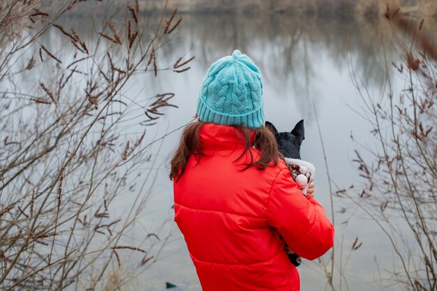 Chica en ropa de invierno. Adolescente una chaqueta naranja, sombrero azul. Niña y chihuahua.