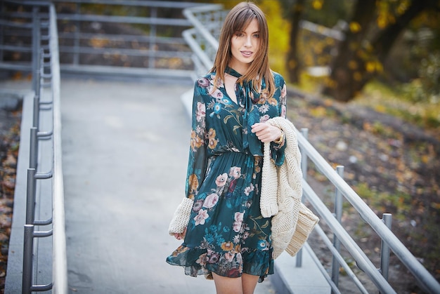 Una chica con ropa de marca está caminando en un parque de otoño