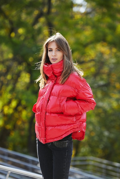 Una chica con ropa de marca está caminando en un parque de otoño