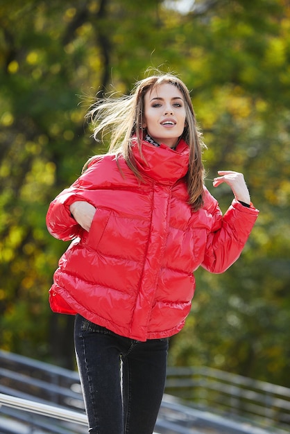 Una chica con ropa de marca está caminando en un parque de otoño