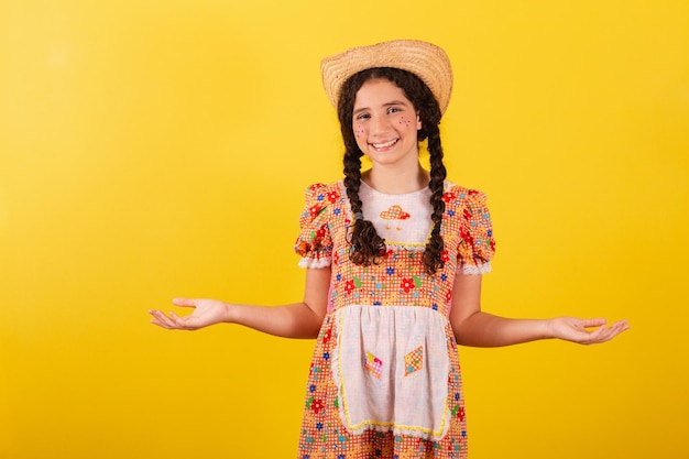 Chica con ropa naranja tradicional para festa junina Con los brazos abiertos bienvenidos