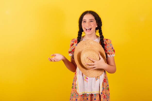 Chica con ropa naranja tradicional para festa junina Saludo y sonriente con sombrero