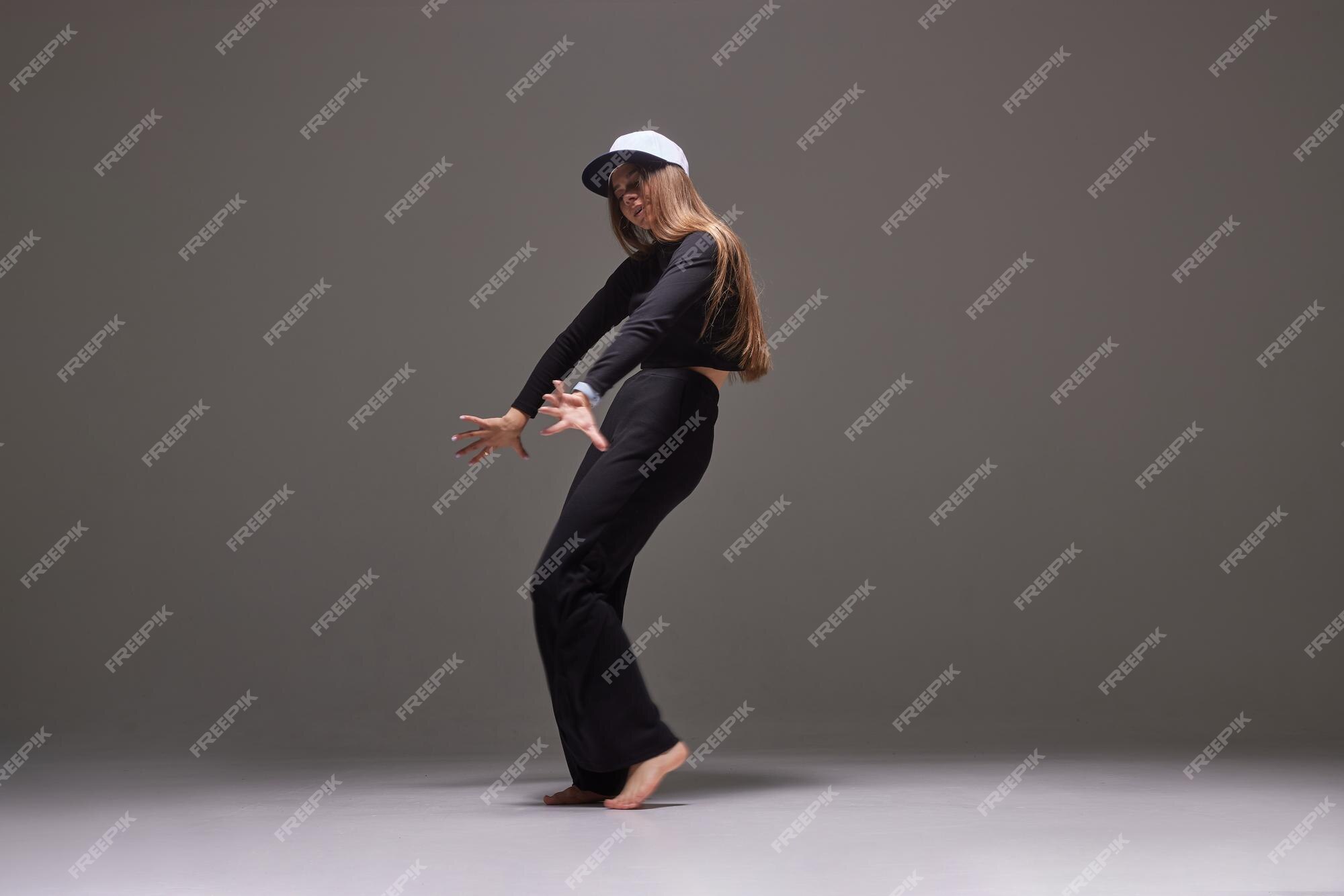 Una chica con ropa oscura baila salta sobre un fondo oscuro danza moderna Foto Premium