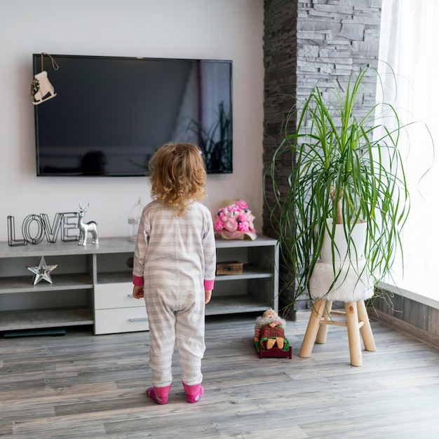 Chica sin rostro mirando televisión